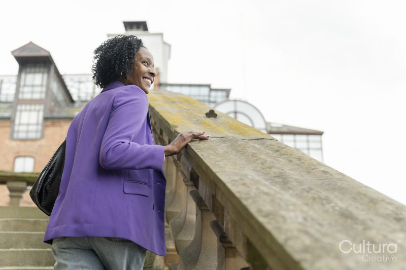Rear view of smiling woman walking on steps and looking at view