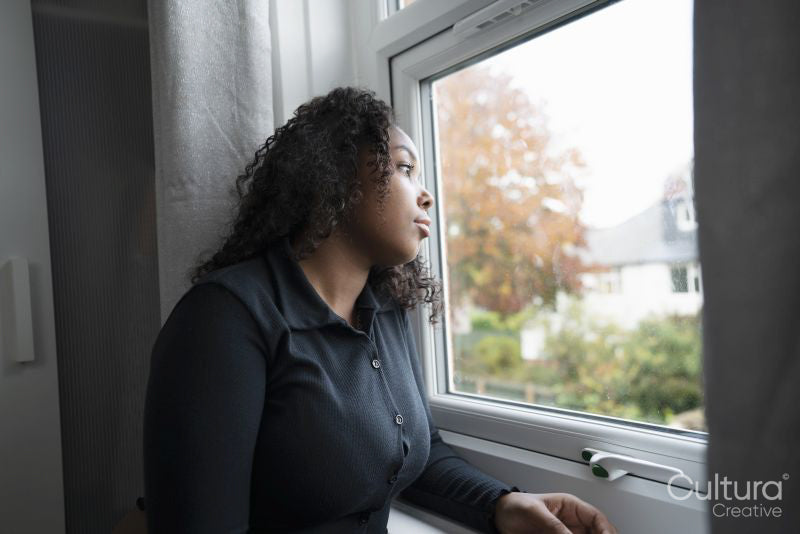 Thoughtful teenage girl looking through window
