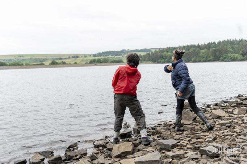 Mother and son skipping stones in lake