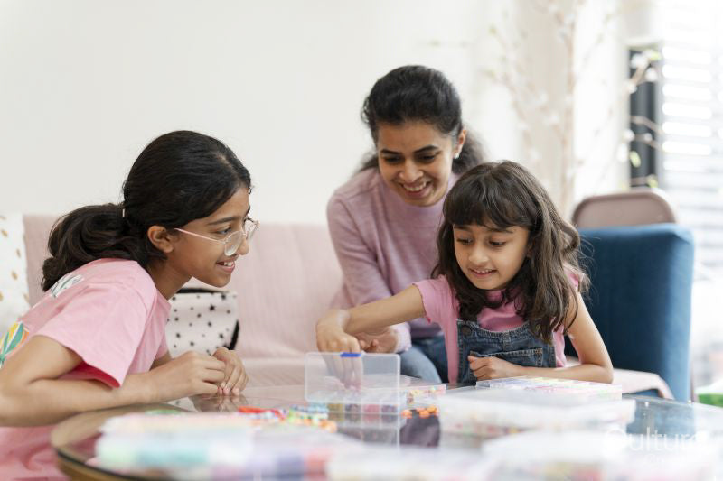 Mother with daughters playing with beads in living room