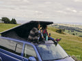 Women sitting on roof of van and looking at landscape