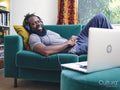 Man lying on sofa,listening to music from laptop