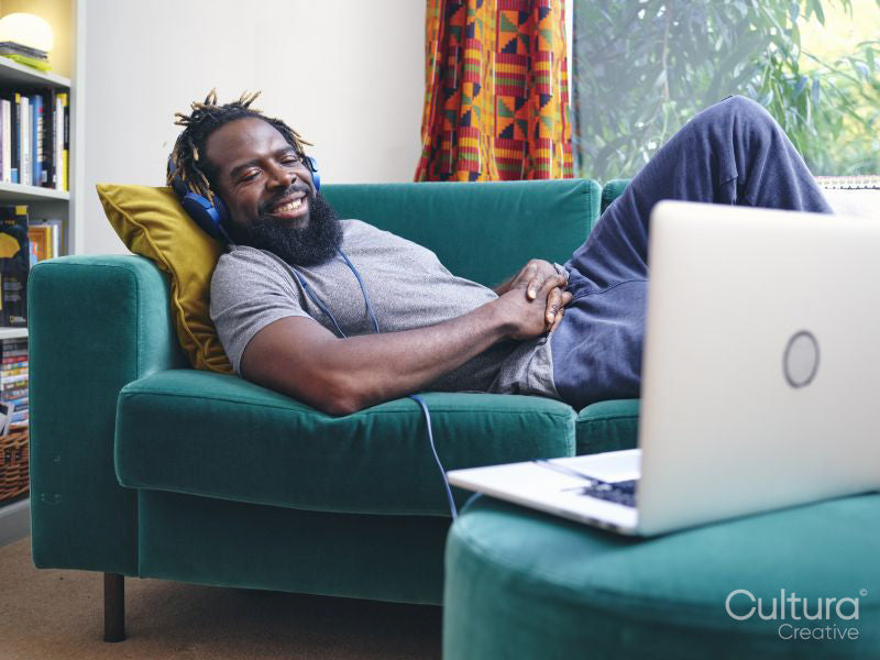 Man lying on sofa,listening to music from laptop