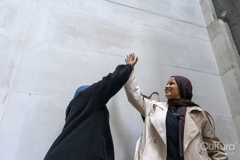 Two women wearing hijabs doing high-five