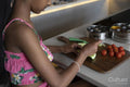 Close-up of girl cutting cucumber in kitchen