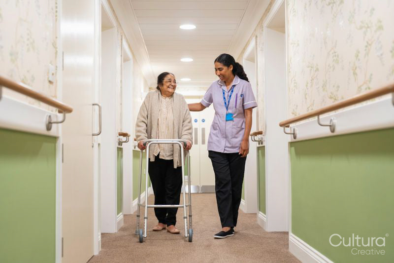 Nurse helping senior lady to walk with mobility walker at nursing home