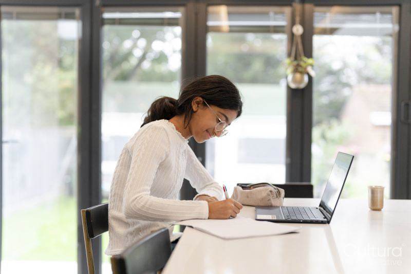 Girl doing homework and using laptop in living room