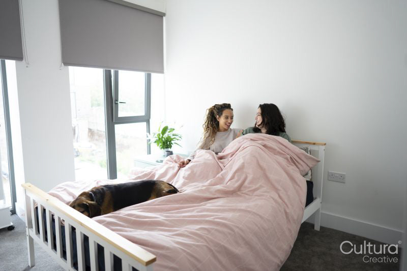 Two women and dog relaxing on bed