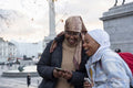 Young female tourists in hijabs using phone in Trafalgar Square