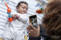 Mother photographing baby daughter with smart phone at home