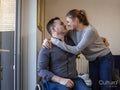 Woman embracing man on wheelchair at home