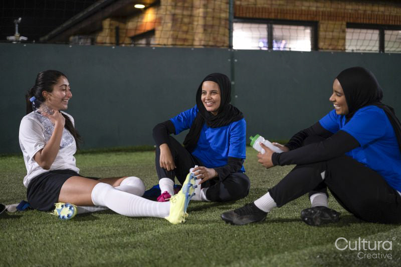 Female soccer players sitting and laughing
