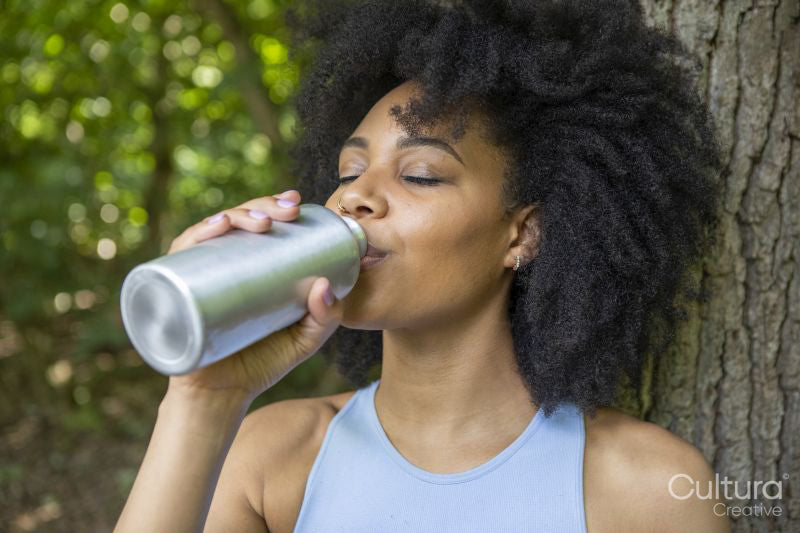 Young woman drinking water in forest