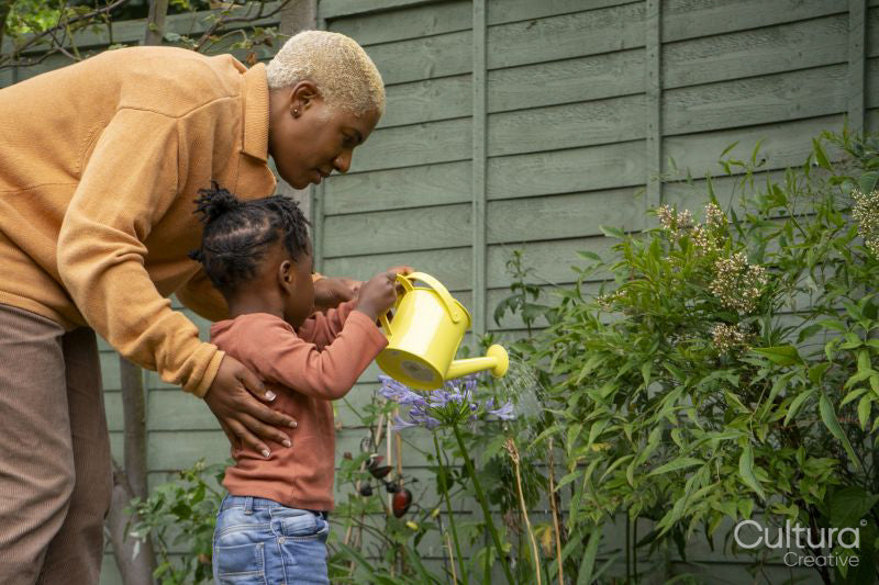 Mother and daughter watering plants in garden