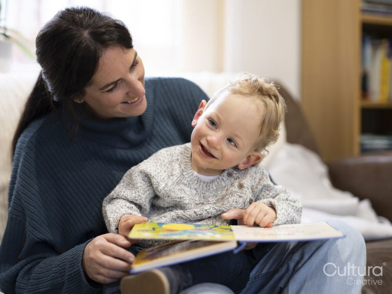 Smiling boy sitting on mothers lap and looking away
