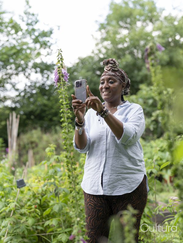 Mature woman photographing flowers in garden
