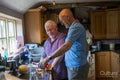 Senior male couple pouring drinks in kitchen