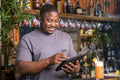 Smiling bartender using tablet at bar