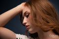 Woman in a polka dot top posing with hand on head