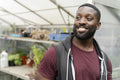Portrait of smiling man standing in front of greenhouse