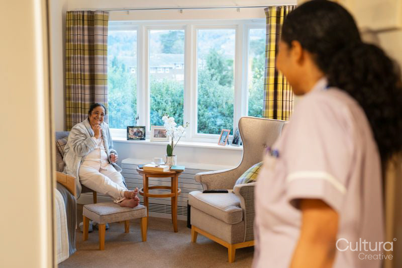 Nurse visiting senior lady in her room at nursing home