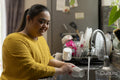Young woman with down syndrome washing dishes at home