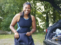 Portrait of smiling woman putting on wetsuit