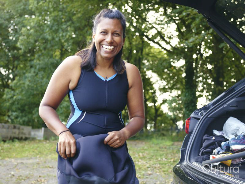 Portrait of smiling woman putting on wetsuit