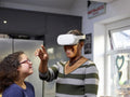 Girl with Down Syndrome looking at mother wearing VR goggles