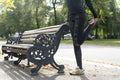 Low section of woman stretching leg at bench in park