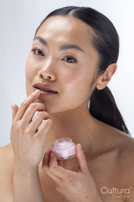 Studio portrait of woman applying lip balm