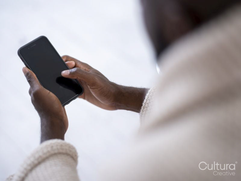 Close-up of person wrapped in blanket holding smart phone