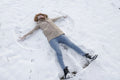 Woman making snow angel in winter landscape