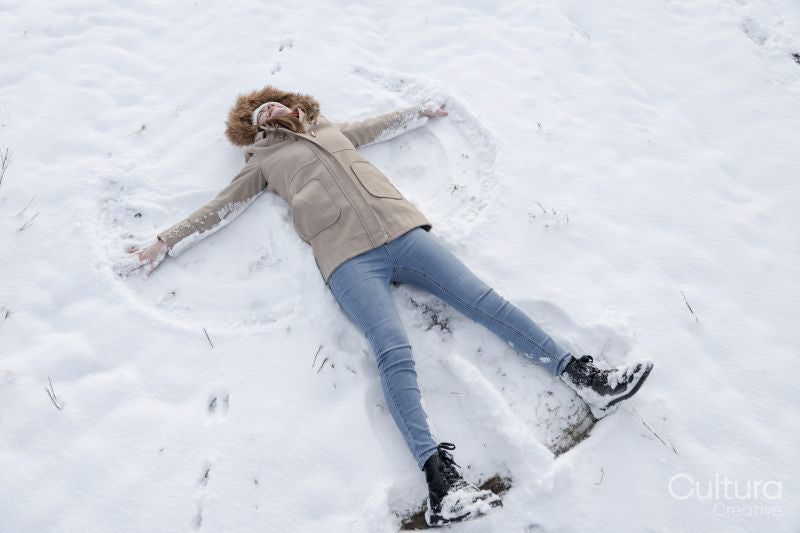 Woman making snow angel in winter landscape