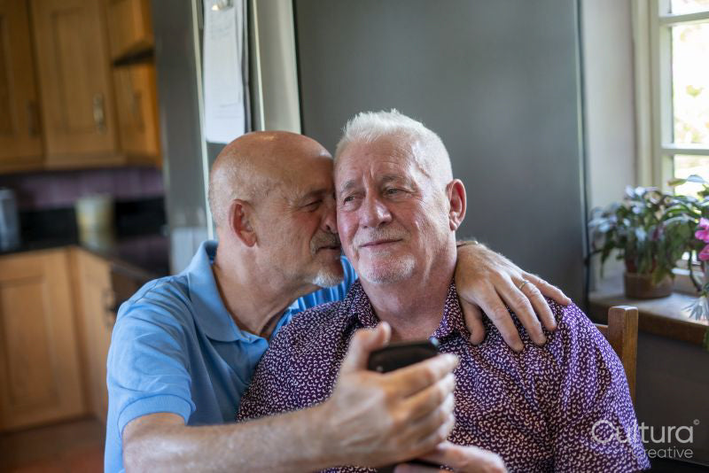 Senior male couple using smart phone at home