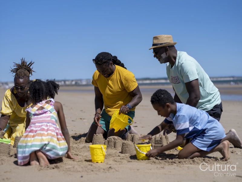 Family with children building sand castles on beach