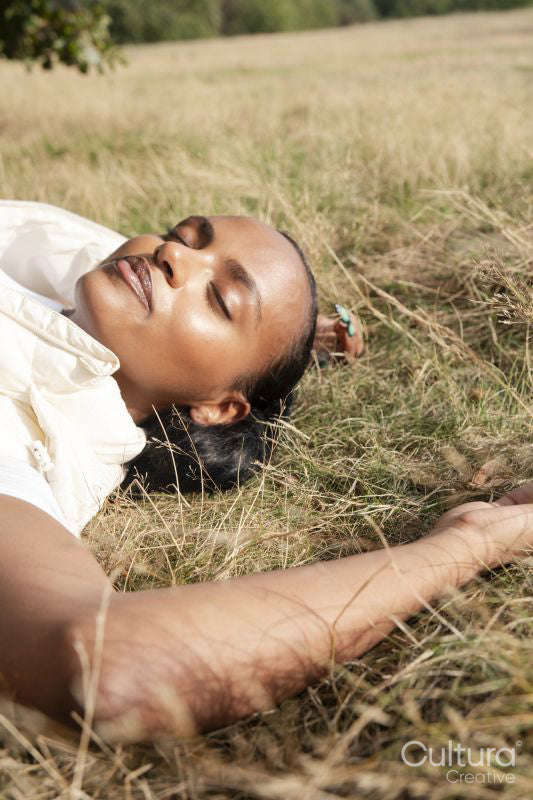 Portrait of young woman lying in grassy field