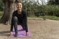 Portrait of smiling woman in low lunge pose in park