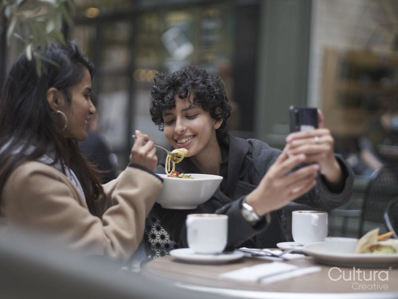 Female couple taking selfie in restaurant while eating