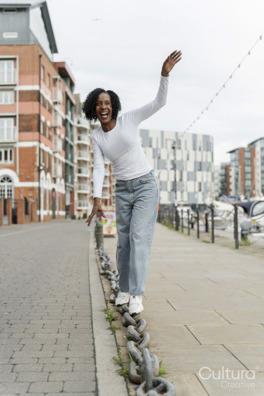 Smiling woman balancing on chain link in city