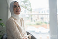 Smiling woman in hijab sitting in chair at home