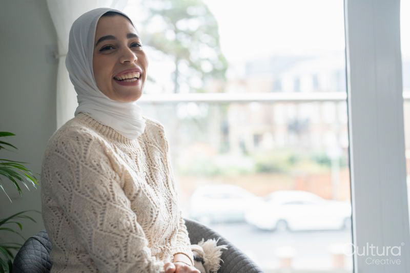 Smiling woman in hijab sitting in chair at home