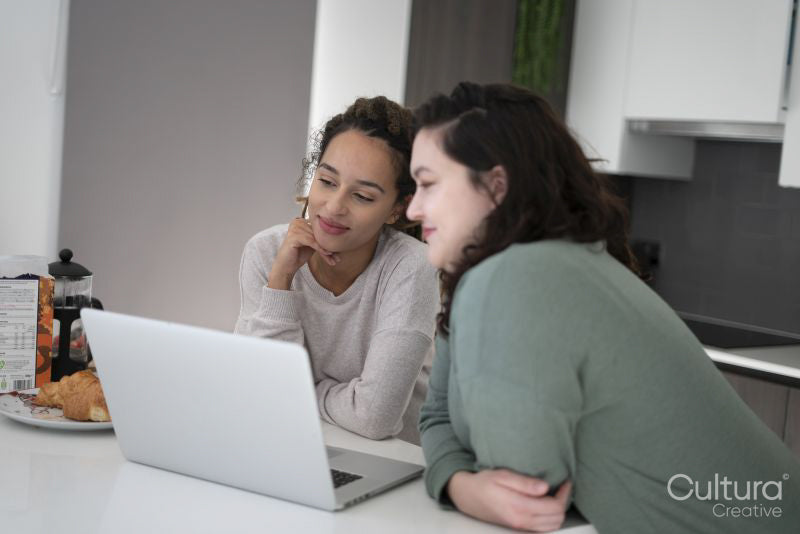 Two women looking at laptop in kitchen