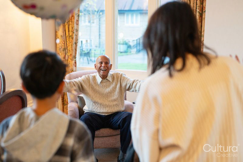 Happy senior man greeting daughter and grandson during visit in nursing home