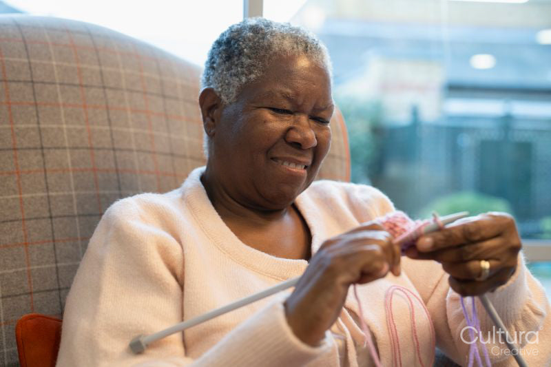 Smiling senior woman knitting in nursing home