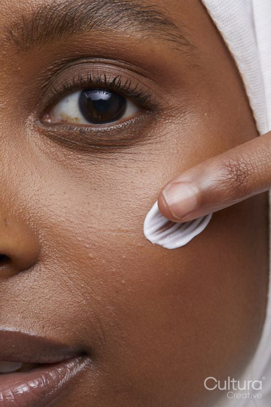 Studio shot of young woman in white hijab applying face cream