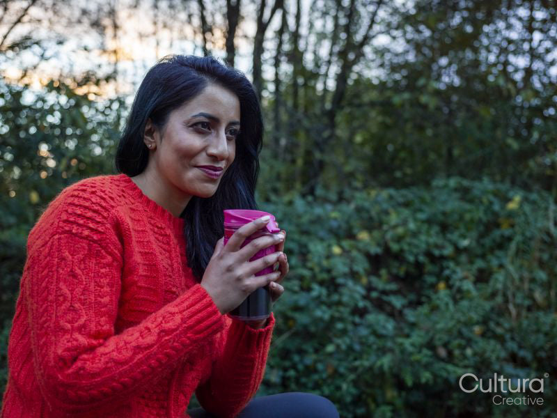 Woman drinking hot drink in forest