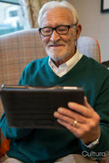 Senior man sitting in armchair and using tablet in nursing home