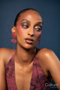 Woman in a burgundy dress with red earrings on a blue background