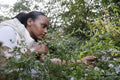 Portrait of woman looking at flowers on bush